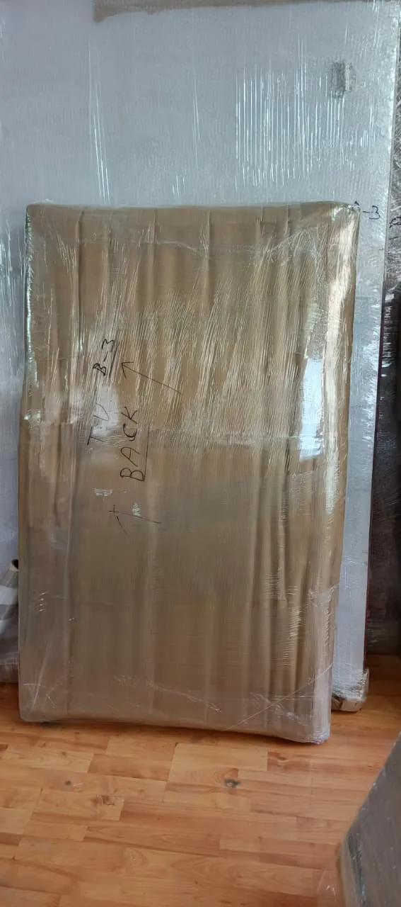 Flat-screen TV packed in cardboard and stretch film, hand-labelled TV B-3 Back