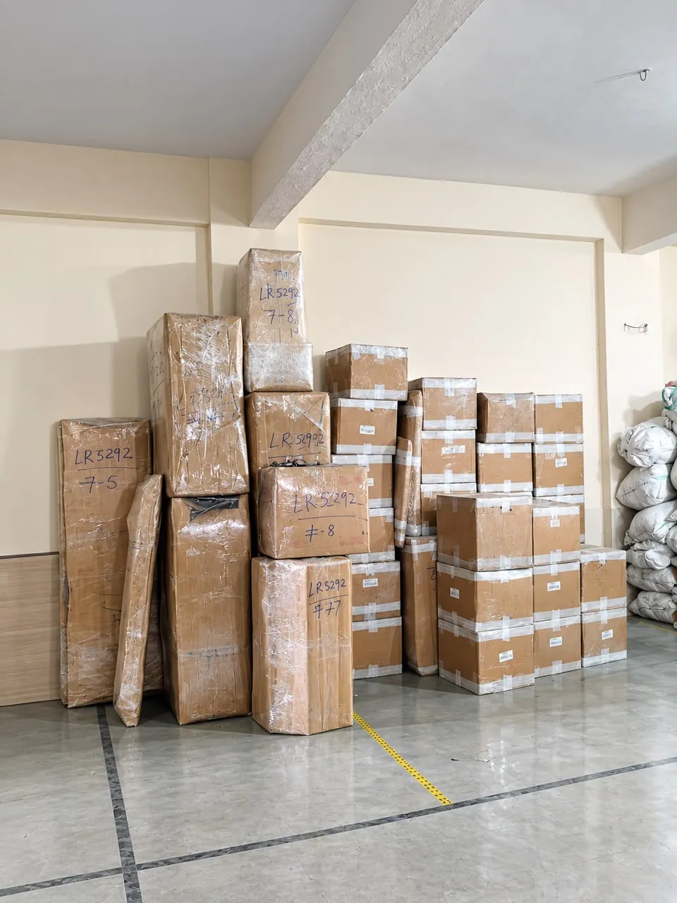 Stack of shrink-wrapped cartons and furniture marked with a lot number in a clean storage room